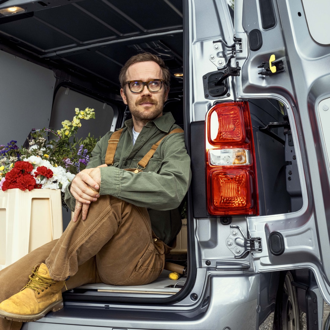 Vue arrière du PEUGEOT Expert avec portes ouvertes et personne assise à l’arrière du véhicule